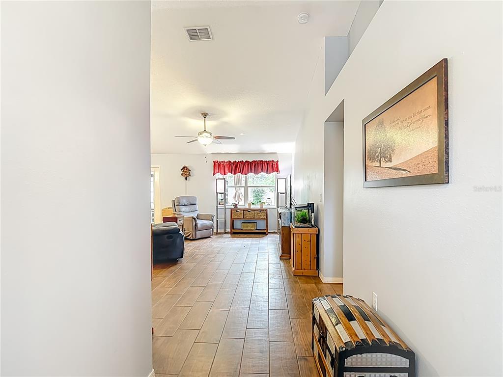 A hallway leads into a living room with wood-look tile flooring and a ceiling fan — 6353 CARDINAL CREST DRIVE, NEW PORT RICHEY, FL