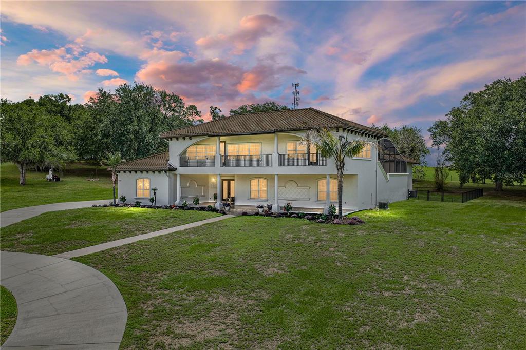 A two-story stucco house with a tiled roof, balcony, and a curved concrete driveway — 37624 SKY RIDGE CIRCLE, DADE CITY, FL