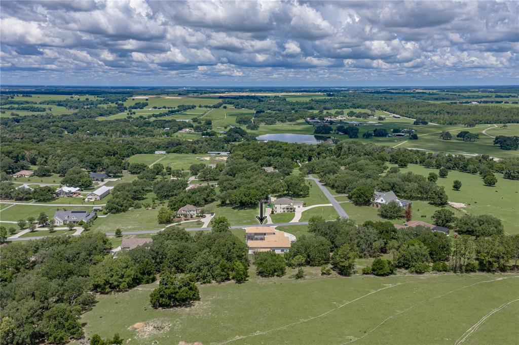 An aerial view shows a house with a pool cage surrounded by rural green fields — 37624 SKY RIDGE CIRCLE, DADE CITY, FL