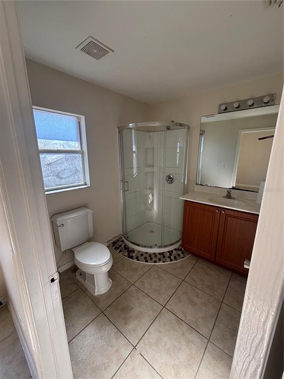 A bathroom features a corner shower, a single-sink vanity, a toilet, and tile flooring — 2429 NOBEL AVENUE UNIT 2431, LEHIGH ACRES, FL