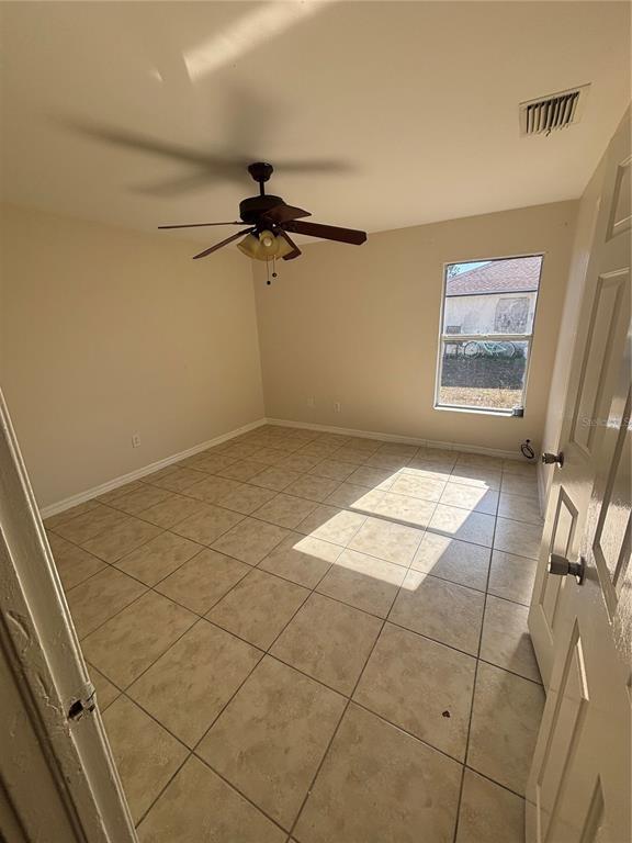 A bedroom with beige walls, a ceiling fan, and light-colored tile flooring — 2429 NOBEL AVENUE UNIT 2431, LEHIGH ACRES, FL