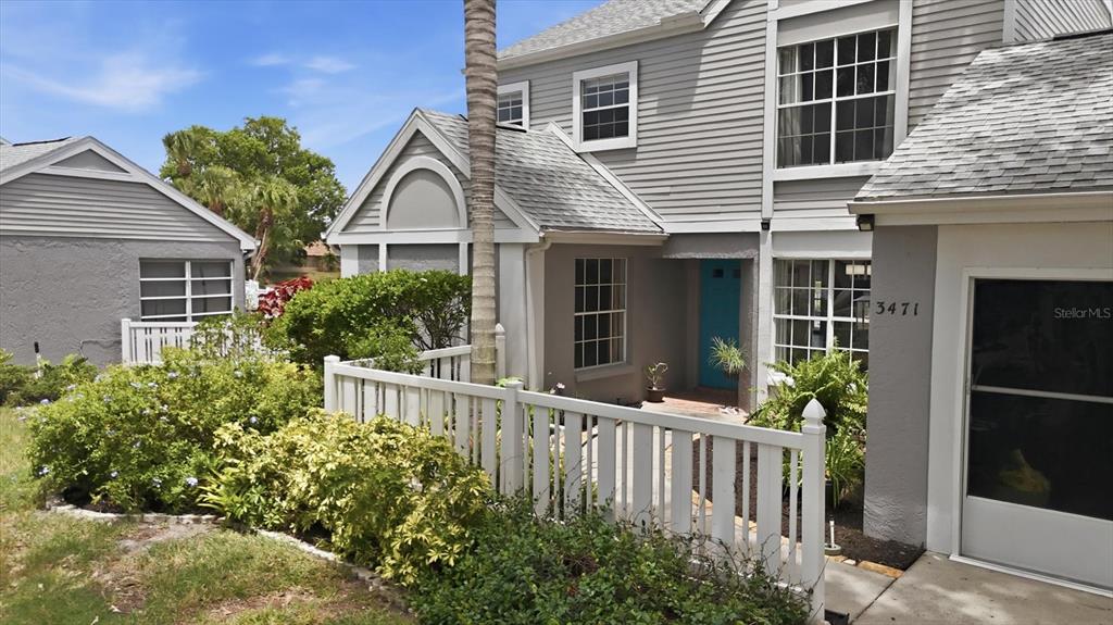 A two-story house with gray siding, a white picket fence, and a bright blue front door — 3471 51ST AVENUE CIRCLE W, BRADENTON, FL