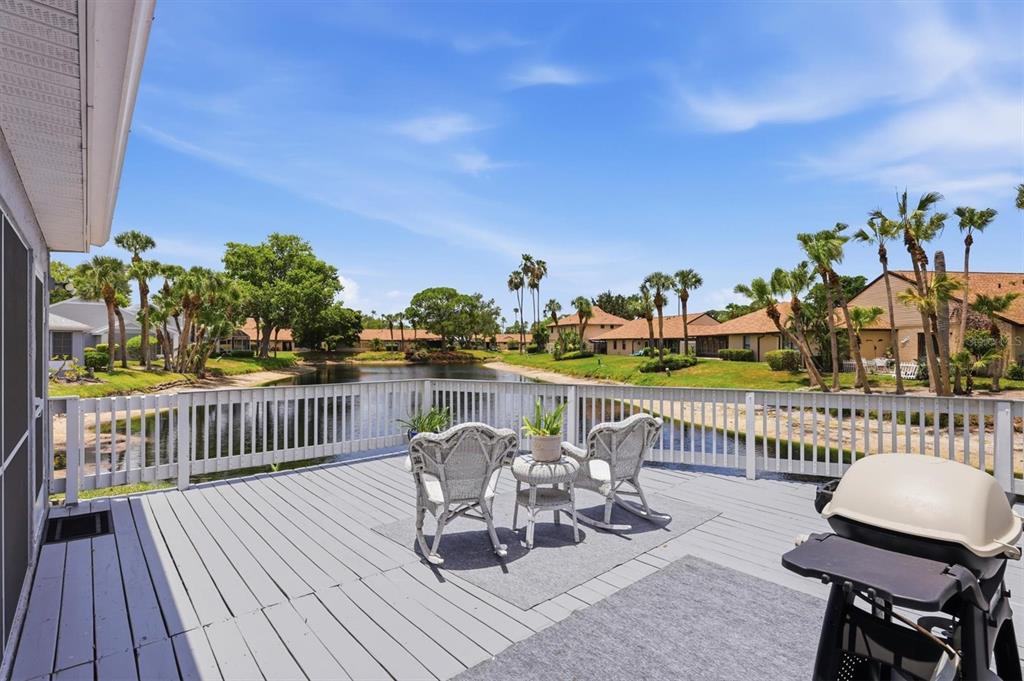A wooden deck overlooks a small pond surrounded by houses and palm trees — 3471 51ST AVENUE CIRCLE W, BRADENTON, FL