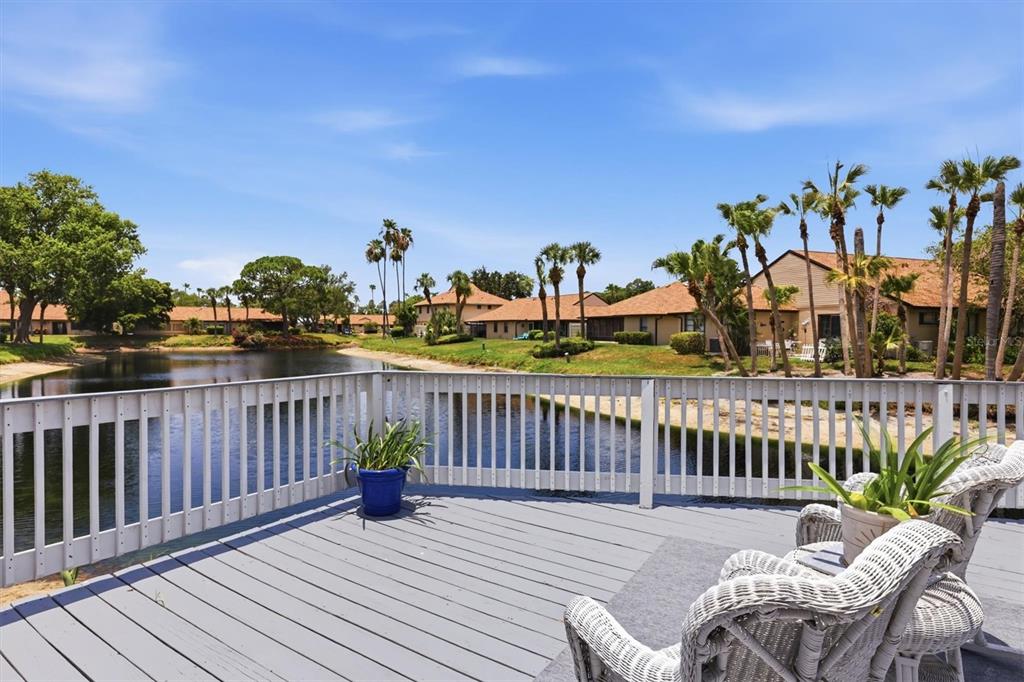 A wooden deck with white railings overlooks a pond surrounded by houses and palm trees — 3471 51ST AVENUE CIRCLE W, BRADENTON, FL