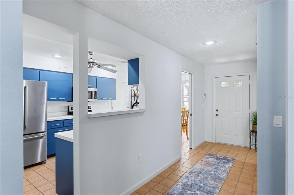 A view from a hallway looking into a kitchen with blue cabinets and a pass-through — 3471 51ST AVENUE CIRCLE W, BRADENTON, FL