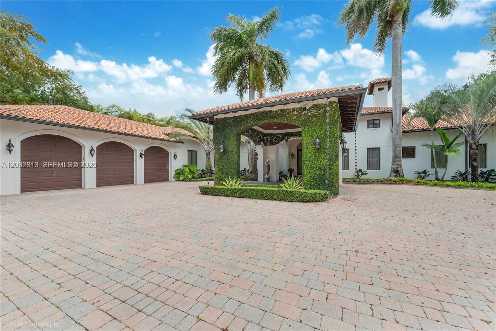 A large Mediterranean-style house features a vine-covered porte-cochère and a paved circular driveway — 7405 SW 104th St, Pinecrest FL 33156, PINECREST, FL