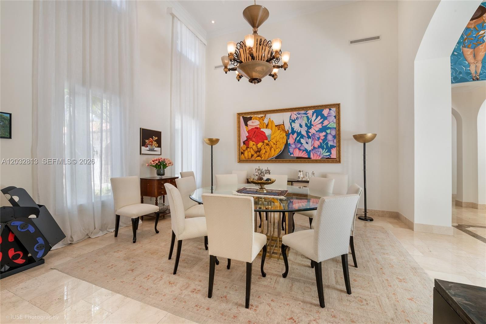 A formal dining room features a glass table, upholstered chairs, a chandelier, and large artwork — 7405 SW 104th St, Pinecrest FL 33156, PINECREST, FL