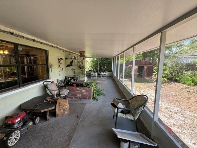 A covered screened-in porch features a concrete floor, a lawnmower, and outdoor furniture — 3763 KOSTEN PLACE, SARASOTA, FL