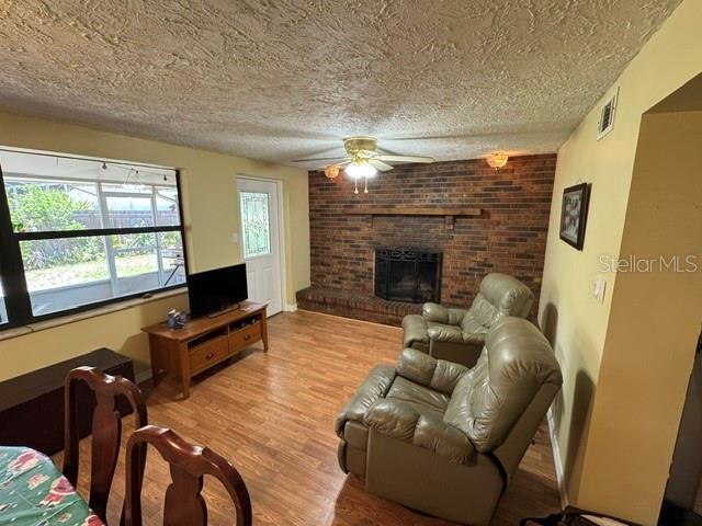 A living room features a brick fireplace, wood-look flooring, and two tan leather recliners — 3763 KOSTEN PLACE, SARASOTA, FL