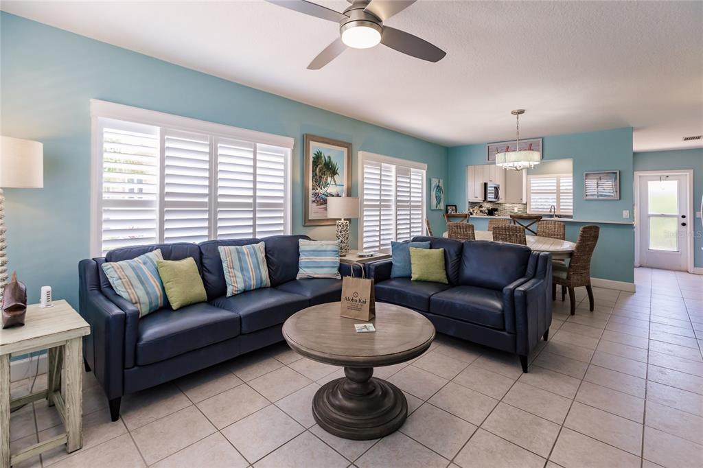 A living room features blue leather sofas, a round coffee table, and light tile flooring — 6020 MIDNIGHT PASS ROAD UNIT 2, SARASOTA, FL
