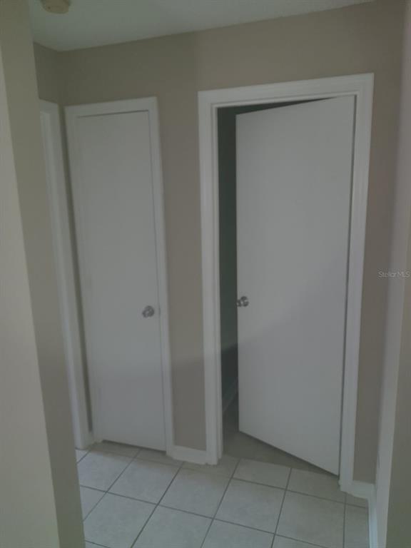 A hallway with light-colored tile flooring features two white interior doors against beige walls — 5962 WESTGATE DRIVE UNIT 204, ORLANDO, FL