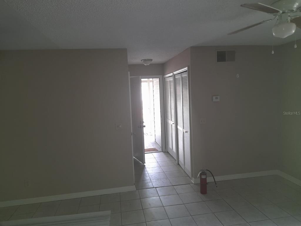 An interior view shows a tiled entryway with a fire extinguisher and louvered closet doors — 5962 WESTGATE DRIVE UNIT 204, ORLANDO, FL