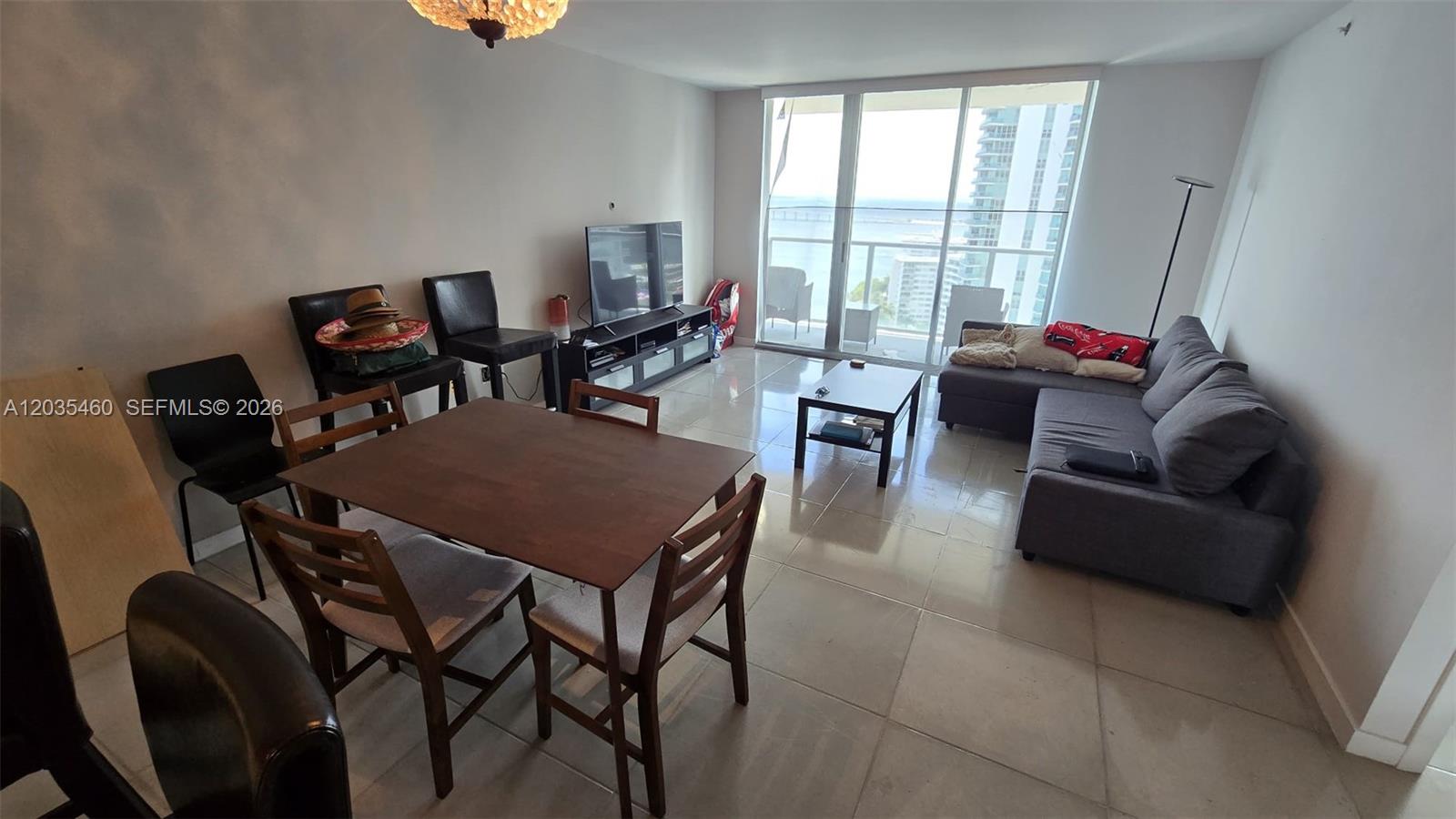 A living and dining area features tile floors, a gray sectional, and floor-to-ceiling windows — 1155 Brickell Bay Dr # 2507, Miami FL 33131, MIAMI, FL