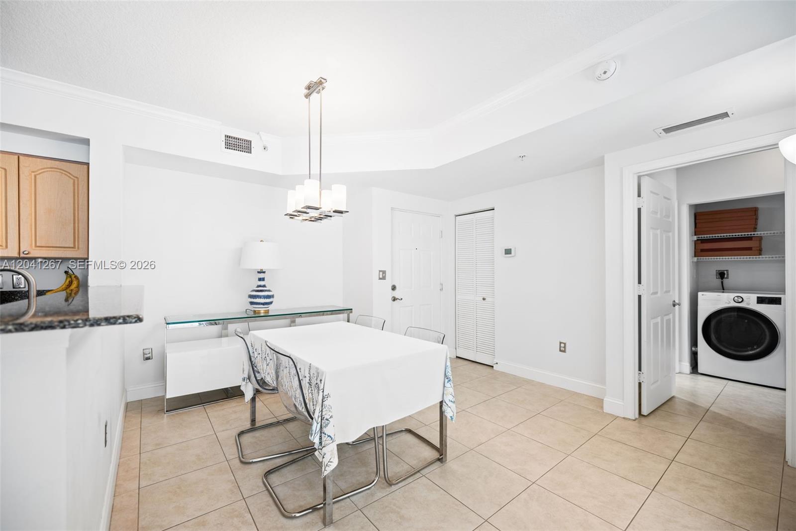 A dining area features a white table, modern chairs, tile flooring, and an adjacent laundry closet — 6861 SW 44th St # 202, Miami FL 33155, MIAMI, FL