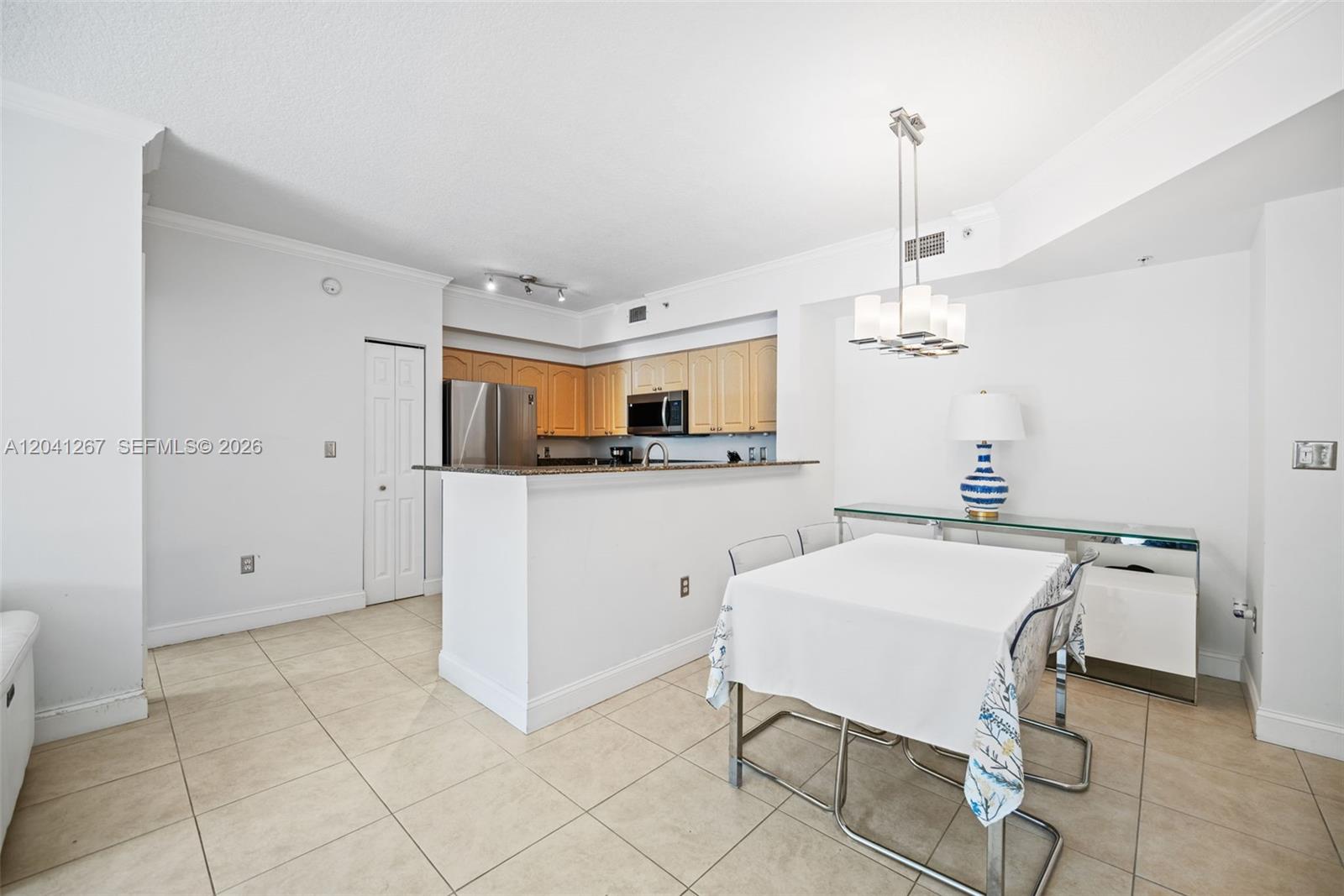 A kitchen with light wood cabinets and a granite breakfast bar overlooks a dining area — 6861 SW 44th St # 202, Miami FL 33155, MIAMI, FL