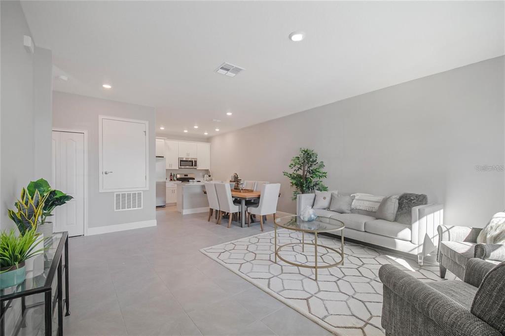 An open-concept living and dining area features light gray tile floors and white kitchen cabinetry — 1805 CORIANDER DRIVE UNIT 1805, POINCIANA, FL
