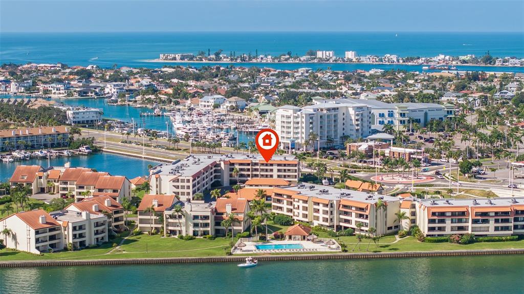 An aerial view shows a multi-story waterfront condominium complex with a pool and boat slips — 106 1ST STREET E UNIT 315, TIERRA VERDE, FL