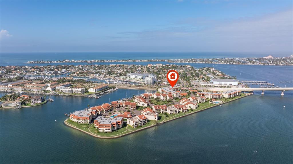 An aerial view shows a waterfront condominium complex surrounded by a bay and bridge — 106 1ST STREET E UNIT 315, TIERRA VERDE, FL