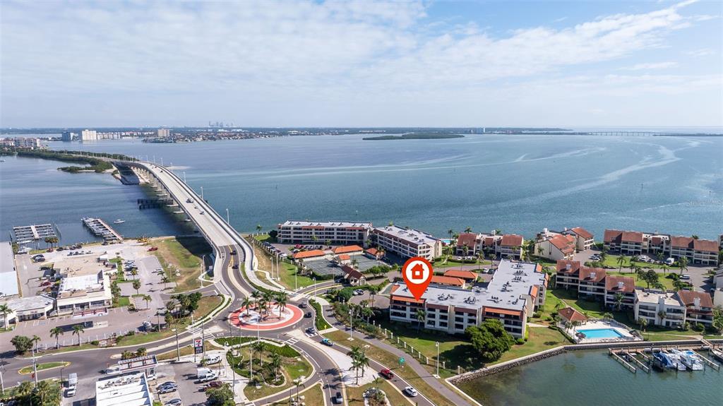 An aerial view shows a waterfront condominium complex near a bridge and a roundabout — 106 1ST STREET E UNIT 315, TIERRA VERDE, FL