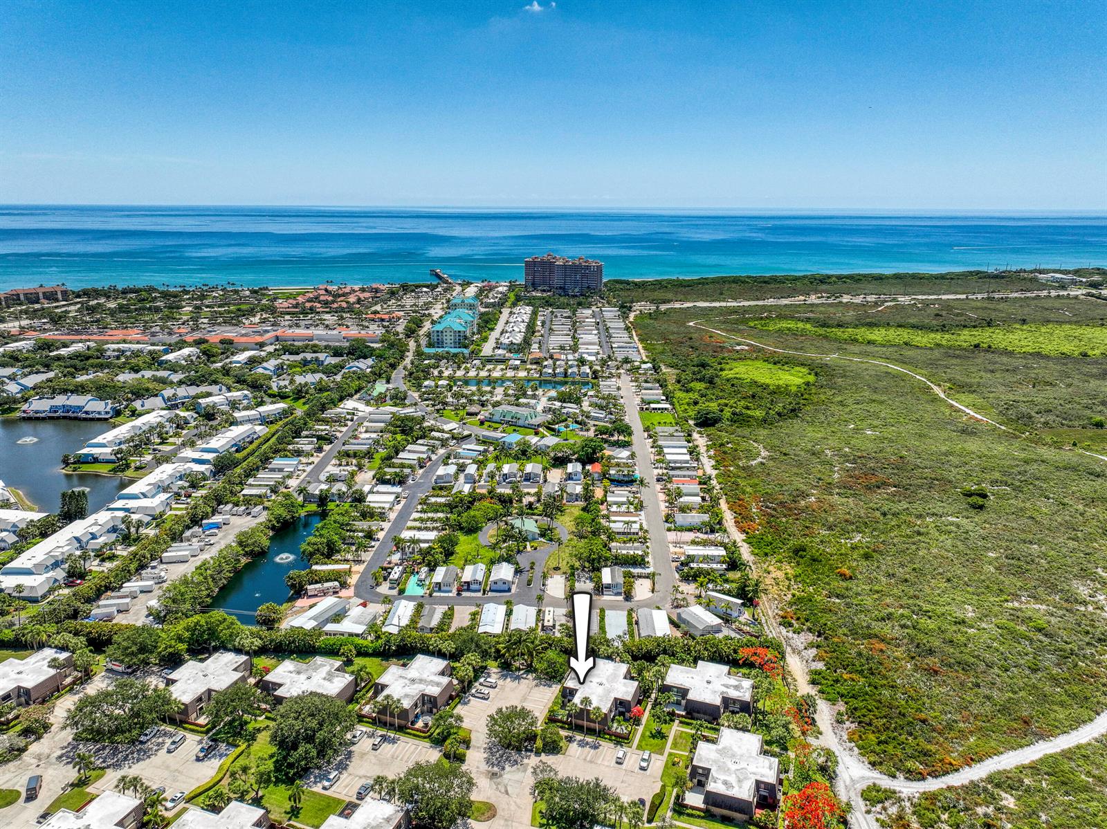 An aerial view shows a residential community with a white arrow pointing to a building — 1913 19th Court, Jupiter FL 33477, JUPITER, FL