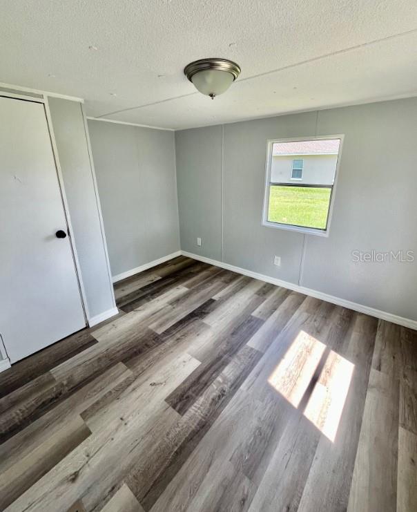 An empty bedroom features light gray walls, a window, and wood-look vinyl plank flooring — 225 ADAMS STREET UNIT A, AUBURNDALE, FL