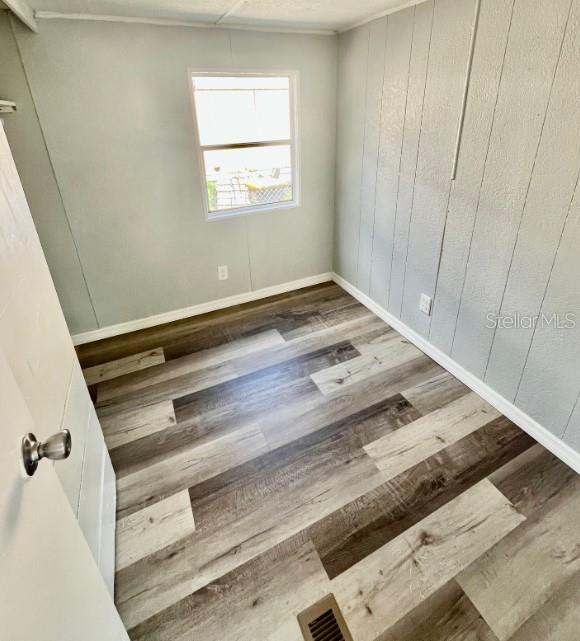 An empty room features light gray paneled walls, a single window, and wood-look laminate flooring — 225 ADAMS STREET UNIT A, AUBURNDALE, FL