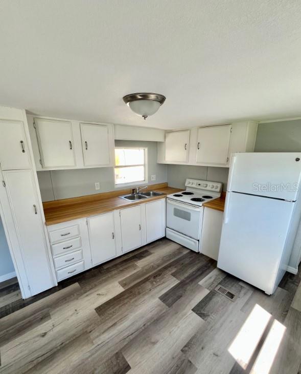 A kitchen features white cabinets, wood-look countertops, a white stove, and a white refrigerator — 225 ADAMS STREET UNIT A, AUBURNDALE, FL