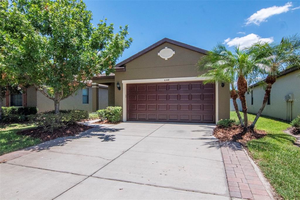 A single-story house with a brown exterior, a two-car garage, and a concrete driveway — 6108 MAGNOLIA PARK BOULEVARD, RIVERVIEW, FL