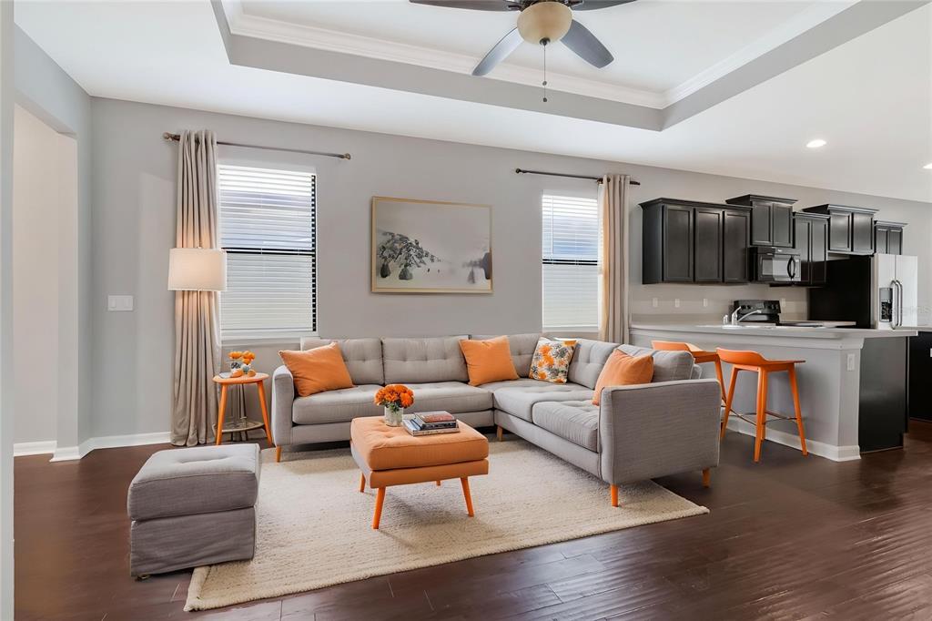 A living room with a grey sectional sofa, orange accents, and an open kitchen — 6108 MAGNOLIA PARK BOULEVARD, RIVERVIEW, FL