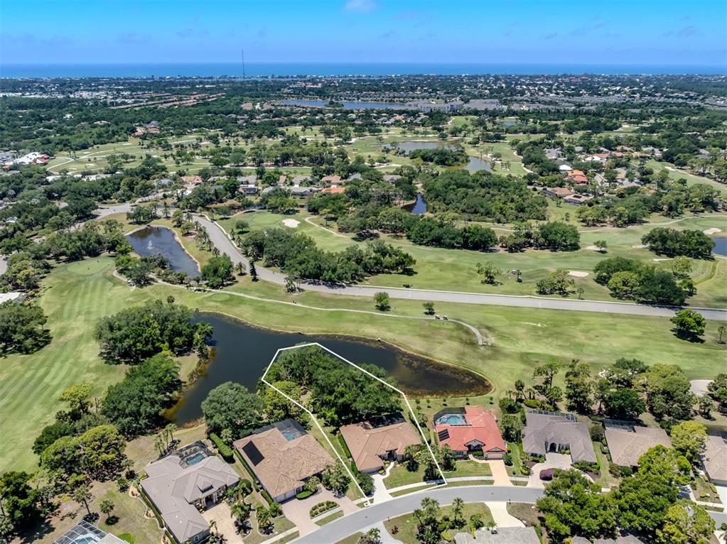 An aerial view shows a single-story house with a pool lot bordering a golf course — 2120 MUSKOGEE TRAIL, NOKOMIS, FL
