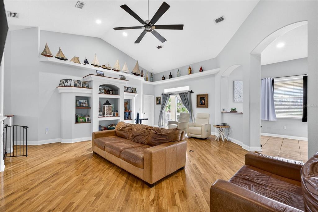 A living room with hardwood floors, a brown leather sofa, and a vaulted ceiling — 7445 GULF WAY, HUDSON, FL