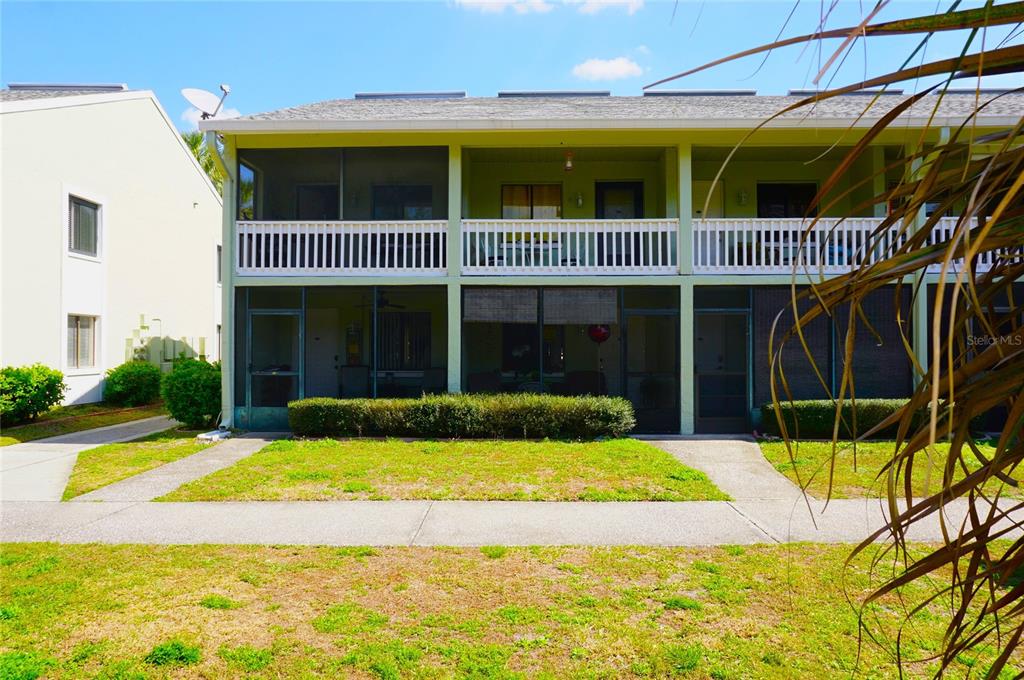 A two-story apartment building features screened-in balconies and patios with a shared front lawn — 20857 HAULOVER COVE UNIT B12, LUTZ, FL