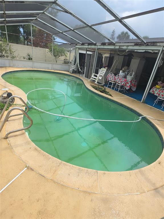 An outdoor swimming pool with green water is enclosed by a screened-in patio area — 1561 AVALON BOULEVARD, CASSELBERRY, FL
