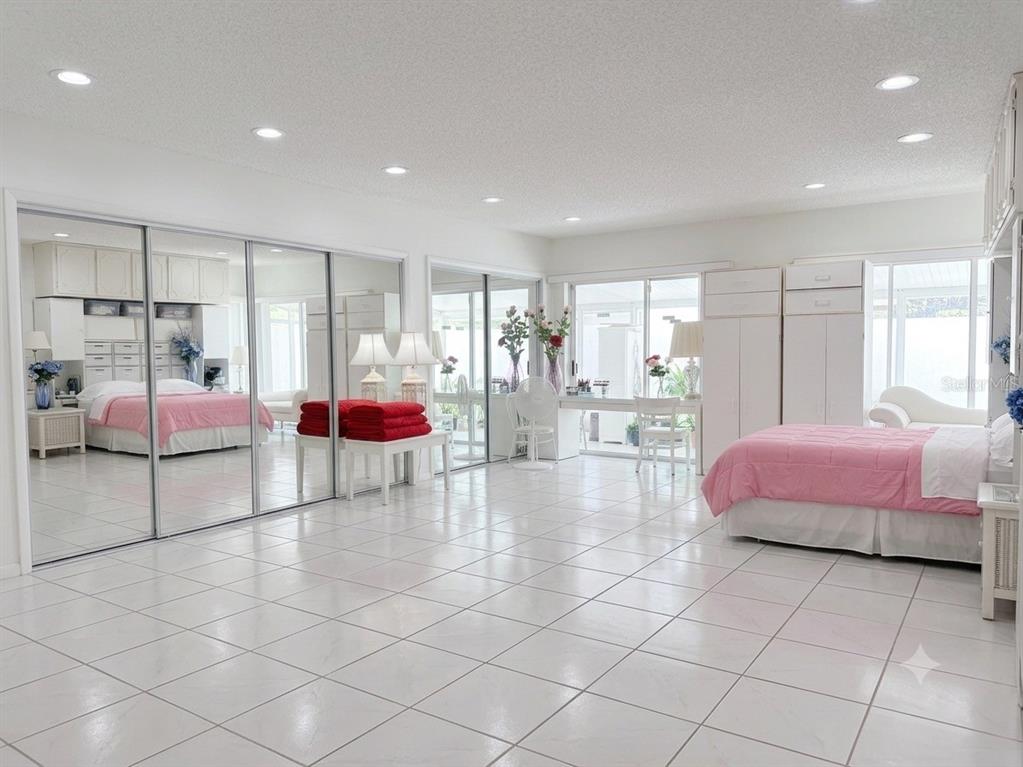 A spacious bedroom with white tile floors, mirrored closet doors, and a pink-comforter bed — 1561 AVALON BOULEVARD, CASSELBERRY, FL