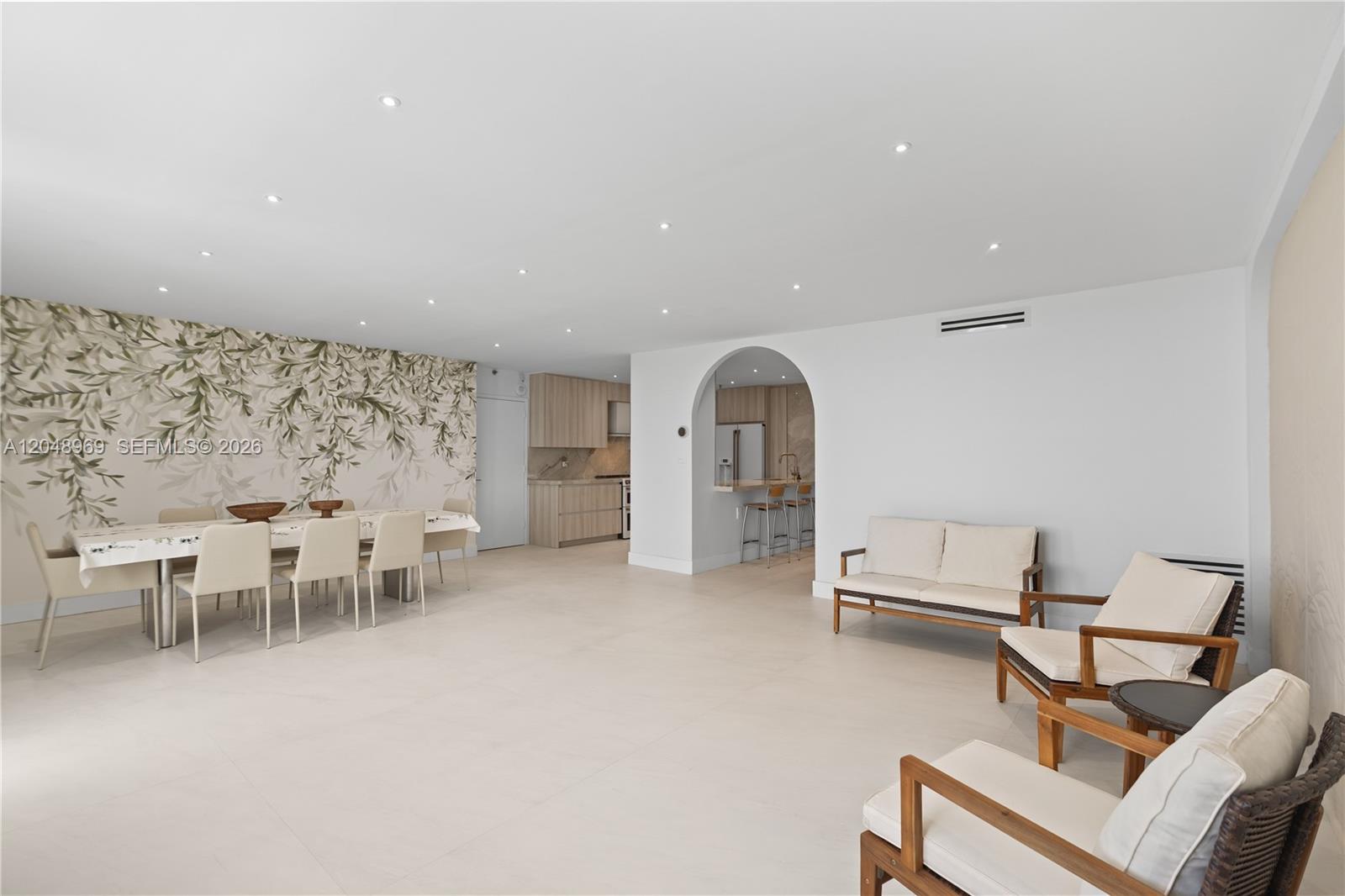 An open-concept living and dining area features white tile floors, recessed lighting, and an arched entryway — 9511 Collins Ave # 403, Surfside FL 33154, SURFSIDE, FL