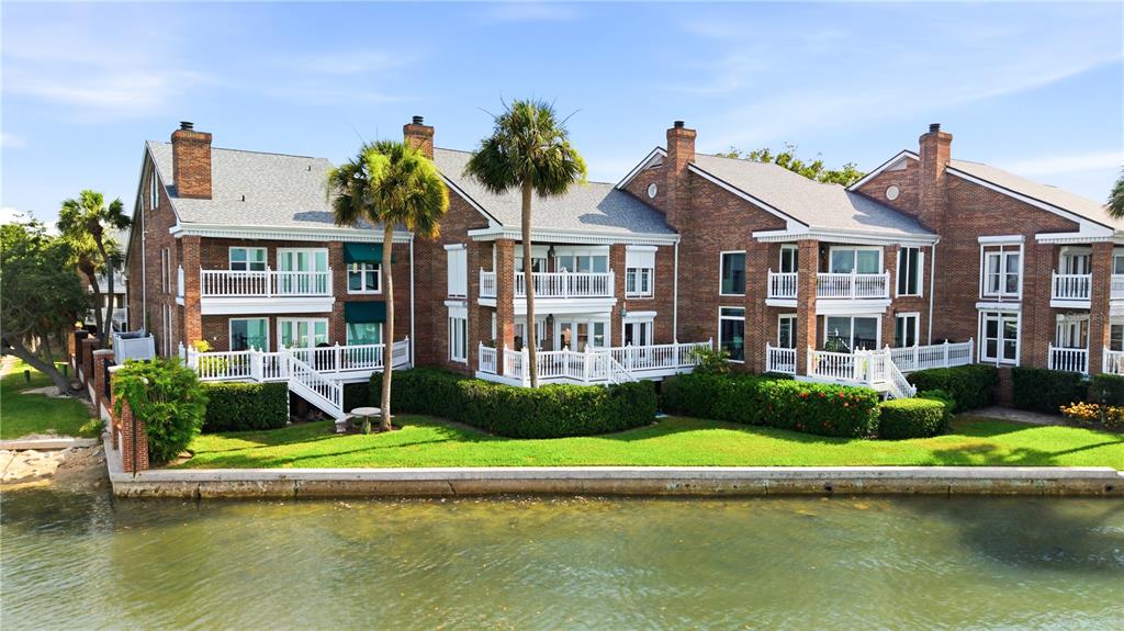 A multi-story brick residential building with balconies sits along a waterfront with a grassy lawn — 5210 INTERBAY BOULEVARD UNIT 3, TAMPA, FL