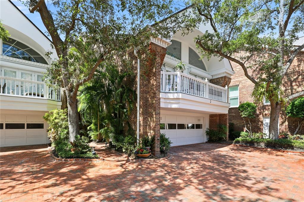 A brick townhouse exterior features white garage doors, a second-story balcony, and mature trees — 5210 INTERBAY BOULEVARD UNIT 3, TAMPA, FL