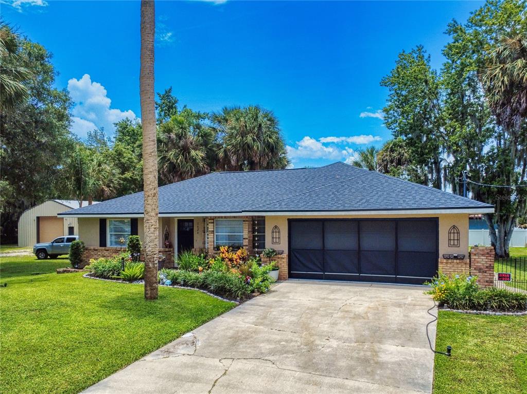 A single-story house with a dark shingled roof, brick accents, and a screened garage door — 1624 CENTER STREET, DELAND, FL