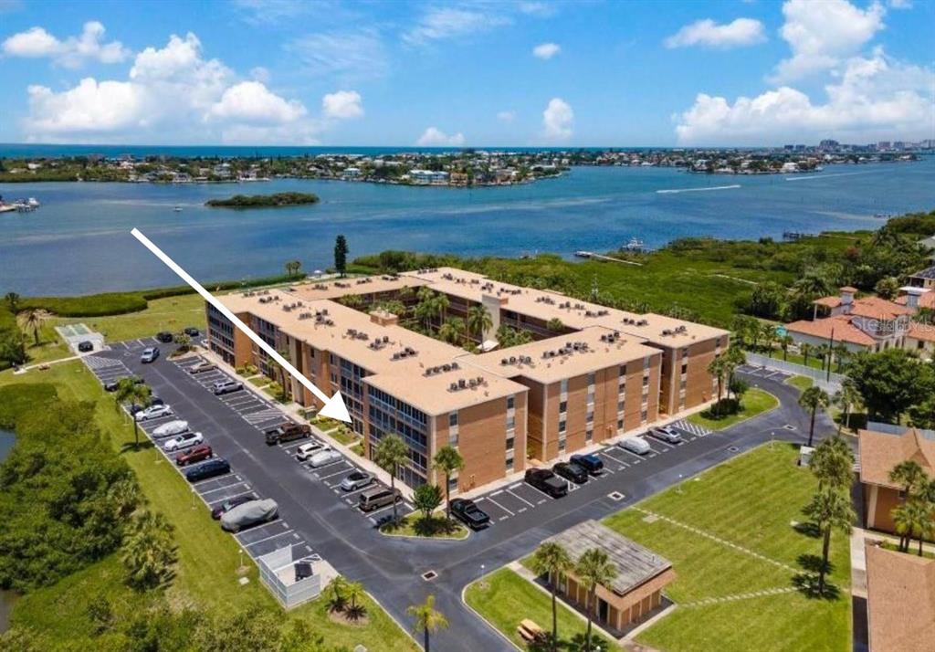 An aerial view of a multi-story apartment building with a parking lot near the water — 12760 INDIAN ROCKS ROAD UNIT 1048, LARGO, FL