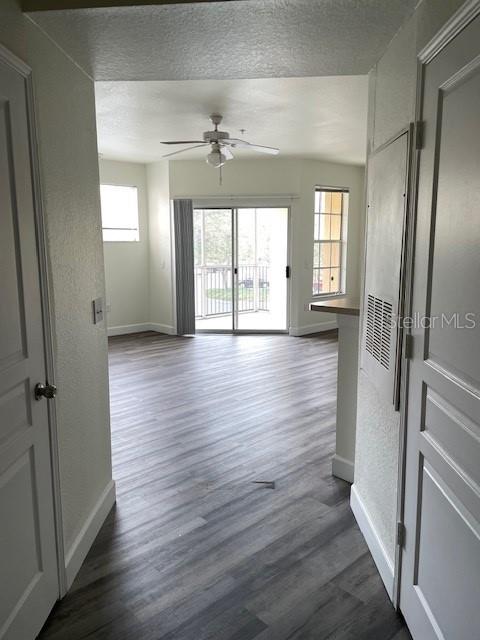 An interior view shows a living area with wood-look flooring, a ceiling fan, and sliding doors — 5125 PALM SPRINGS BOULEVARD UNIT 11203, TAMPA, FL