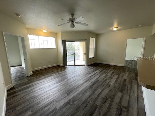 An open-concept living area features wood-look flooring, a ceiling fan, and sliding glass doors — 5125 PALM SPRINGS BOULEVARD UNIT 11203, TAMPA, FL