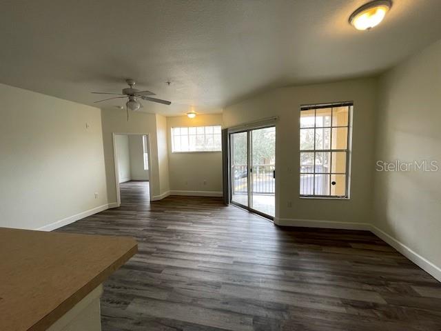 An open living area features wood-look flooring, a ceiling fan, and a sliding glass door — 5125 PALM SPRINGS BOULEVARD UNIT 11203, TAMPA, FL