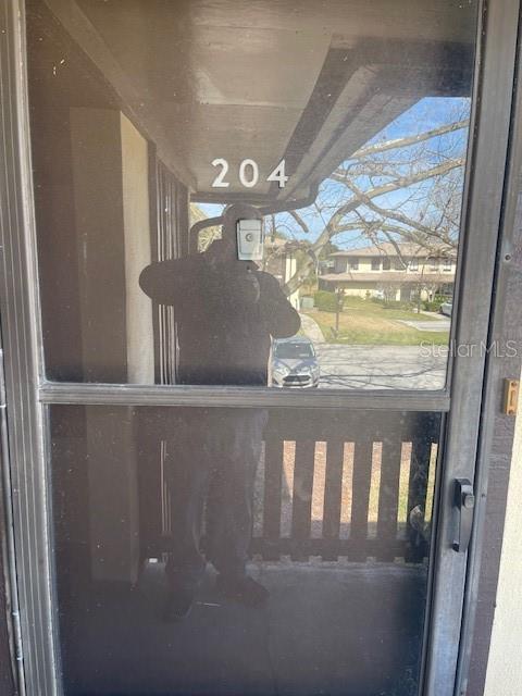A view through a glass storm door showing a building number 204 and a parking lot — 48 CLUB HOUSE DRIVE UNIT 204, PALM COAST, FL