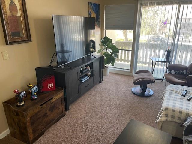 A living room features a television on a dark console, a wooden chest, and seating — 48 CLUB HOUSE DRIVE UNIT 204, PALM COAST, FL