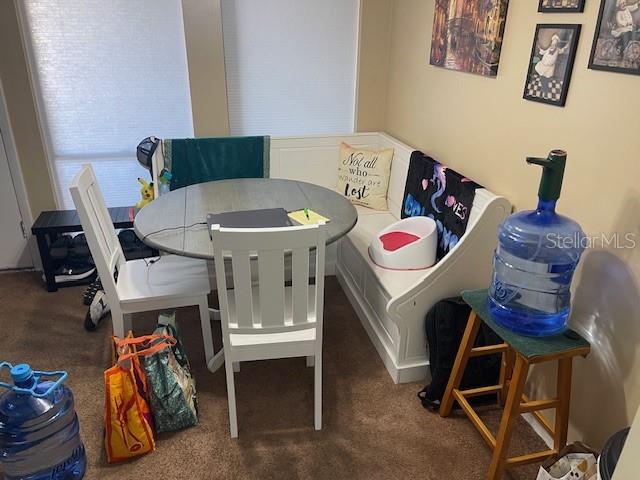 A dining nook features a round table, white chairs, a corner bench, and a water dispenser — 48 CLUB HOUSE DRIVE UNIT 204, PALM COAST, FL