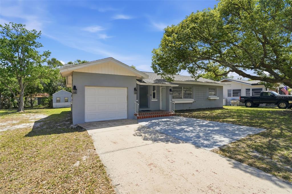 A single-story gray house with a one-car garage, concrete driveway, and a large oak tree — 65 COMMUNITY DR, DEBARY, FL