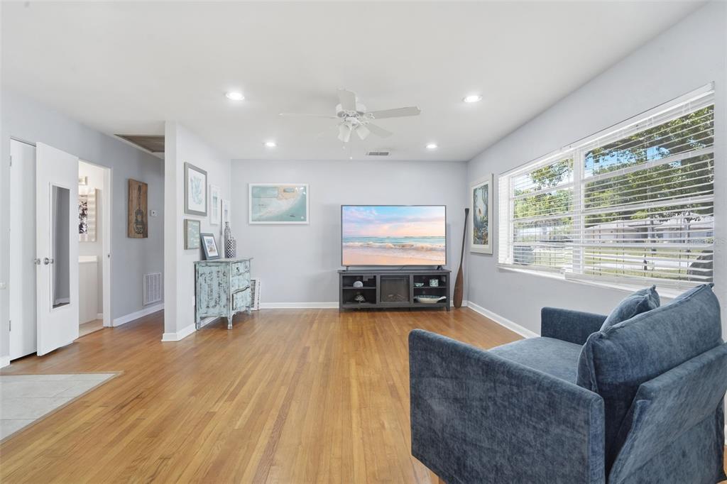 A living room with hardwood floors, a television on a console, and a blue armchair — 65 COMMUNITY DR, DEBARY, FL