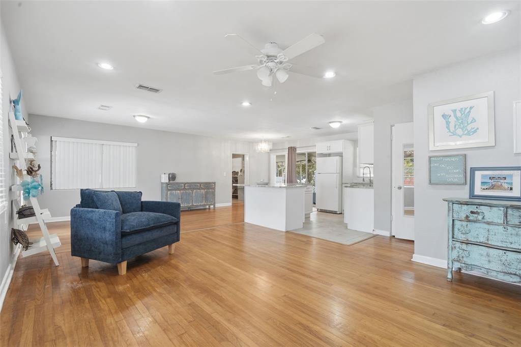 A bright, open-concept living room and kitchen area with hardwood floors and a blue armchair — 65 COMMUNITY DR, DEBARY, FL