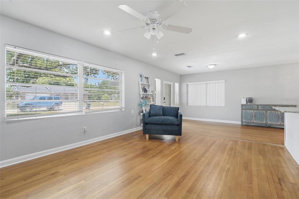A living room with hardwood floors, a blue armchair, and a white ceiling fan — 65 COMMUNITY DR, DEBARY, FL