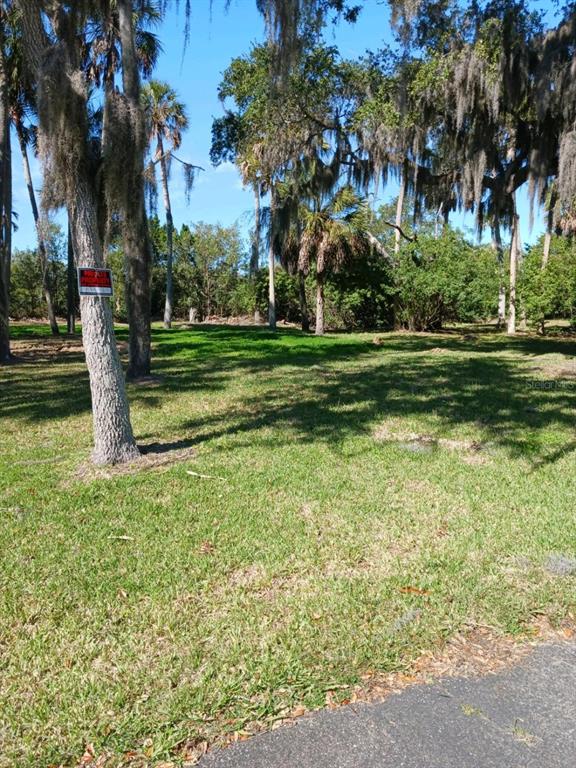A grassy, wooded lot features a private property sign attached to a tree trunk — 5353 TROPICAL WOODS COURT, PORT RICHEY, FL
